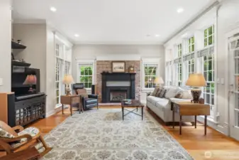 The informal gathering room off the kitchen features walls of windows and gas fireplace with custom mantle.