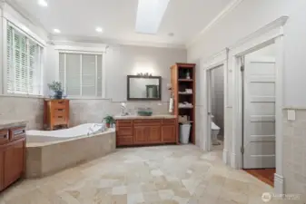The ensuite bathroom features beveled travertine floors, travertine wainscoting around the soaking tub.