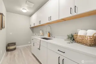 Upper level laundry room with folding counter and utility sink.