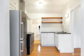 Tiled backsplash, stone counters, and floating shelves. There is also a good size pantry in the background.