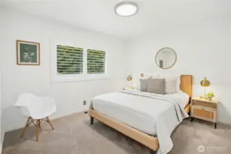 Peaceful secondary bedroom with plush carpet, closet system, and a large window framing lush green views.