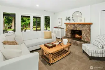 Cozy up fireside in the spacious daylight rec room, featuring a stone hearth, rustic wood mantle, and easy walk-out access to the backyard and expansive patio through French doors.