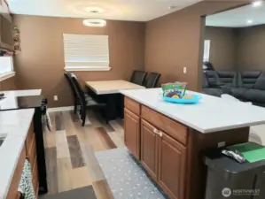 Another View of the Very Spacious Island Kitchen with New Granite Counter Tops, Sink, Faucet, Stainless Appliances, Real Solid Oak Cabinets, LED Lighting, Paint,Trim, and Vinyl Plan Flooring Showing Dining and Living.