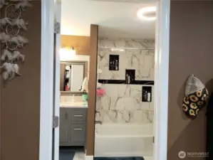 Primary Master Bath Room Showing New Vanity with Granite Counter Top, Tub Tile Surround, Sink, Faucet, Paint, Mirror, LED Lighting and Tile Flooring.