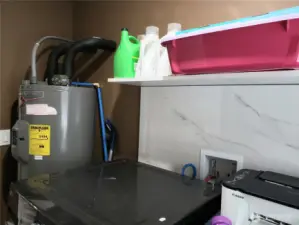A different View of the Nice Size Utility Room with Newer Washer, Dryer, Paint Trim, Shelf and Hot Water Tank.