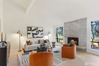 The living room boasts vaulted ceilings with an exposed beam, a cozy wood burning fireplace and large windows overlooking the private grounds.