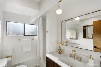 Lower level ¾ bathroom with new shower surround and fixtures, new dark wood vanity, brushed gold faucets and new faux wood mirror.