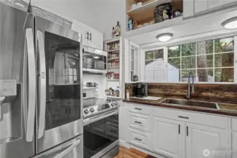 View of your kitchen and included stainless steel appliances. Storage up above is a real plus. I also love the large windows overlooking your huge wrap-around deck.