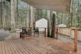 View of your large covered deck to additional storage shed, currently used as a guest bedroom.