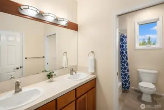 Full bath with dual vanities off the hallway.