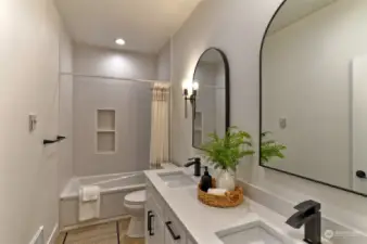 Spa like guest bath has dual undermount sinks and quartz countertops.