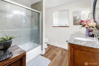 Main bath has luxury vinyl flooring, big vanity and tile tub inset.