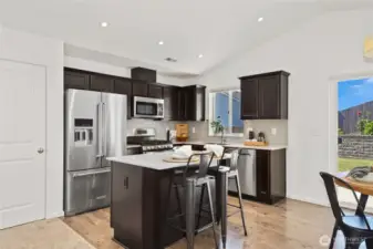 Kitchen sink overlooks the backyard.  The Kitchen features Quartz slab counter tops, tile backsplash and stainless steel appliances.   seating at the kitchen island is perfect for company while you cooke or a quick snack.