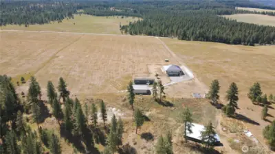 Aerial view. Deer-fenced garden has large green house and raised beds. Areas around the home have underground sprinkler systems that are set up on a timer.