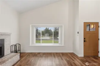Open and light-filled living room with a wood burning fireplace insert, creating a warm welcome upon entry.