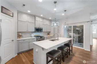 Another angle of the kitchen featuring the generous cabinet space, gas range, and sliding glass door that leads to the covered outdoor living area. The layout brings in lots of natural light and makes indoor-to-outdoor entertaining incredibly easy.