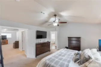A second view of the double door primary bedroom highlighting the vaulted ceiling, neutral paint, and spacious layout. The room flows directly into the ensuite bathroom and offers easy access to the upstairs bonus room, creating a private yet connected retreat.