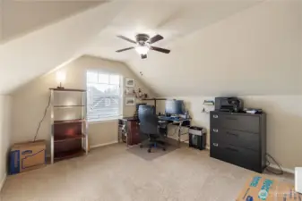A generous office space with a dormer-style ceiling that adds character and charm. The large window brings in natural light, making this an ideal home office, hobby room, or quiet retreat. Plenty of floor space for multiple workstations or storage.