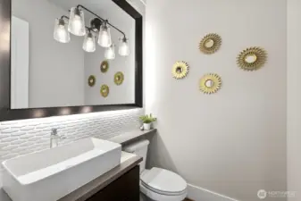 Beautiful powder room on main level with custom mirror surround , back splash and accent lighting.