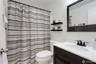 Main hallway bathroom conveniently located between the second and third bedrooms, featuring a new vanity and mirror, plus a full tub and shower combo perfect for family and guests.