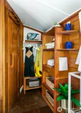 The companionway leads to the captain’s quarters, with efficient built-in shelving and hanging storage crafted from warm wood — keeping essentials organized without sacrificing charm.