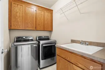 The main floor laundry room offers ample cabinet storage, a deep utility sink, and plenty of space to hang and organize items.