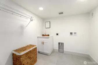 Spacious lower level laundry with non-conforming ceiling heights with shelving + storage.