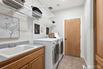 Laundry room connects the home to the garage and includes a utility sink, cabinetry, and closet.