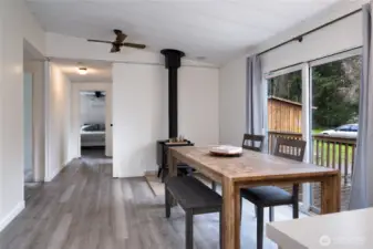Warm and inviting dining space with a rustic wood-burning stove, perfect for cozy gatherings. Sliding glass doors lead to an outdoor deck, seamlessly blending indoor and outdoor living.