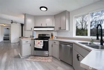 Bright and updated kitchen featuring modern gray cabinetry, sleek black hardware, and durable countertops. The space includes a stylish subway tile backsplash, ample storage, and a clean, functional layout—perfect for everyday living and entertaining.