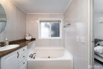 Spa-inspired ensuite bathroom featuring a soaking tub with tile surround, large frosted window for privacy, and plenty of natural light—ideal for relaxation.