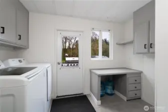 Convenient laundry room with washer and dryer, extra counter space, and storage options. Includes exterior access, adding functionality and practicality.