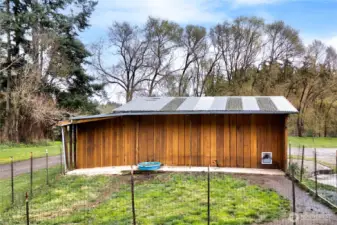 Spacious detached outbuilding with rustic wood siding and durable metal roofing, perfect for use as a barn, workshop, or additional storage. The fenced area adds functionality for animals or equipment, making this property ideal for hobby farming or rural living.