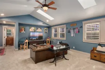 Bonus room on upper level, with vaulted ceilings and skylights, features French doors to a balcony that overlooks the great room. Access to the laundry room is pictured at left.
