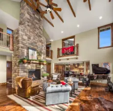 Voluminous great room offers vaulted ceilings with exposed beam architecture, ceiling fans and lighting upgrades.  It opens to dining area, kitchen and planning area.