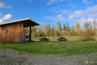 Outdoor kitchen cabana area with picnic tables and fire pit.