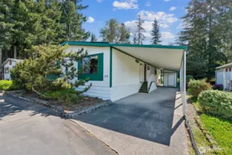 A view of the 2-car tandem carport, back door entrance and paint matching secure storage shed.