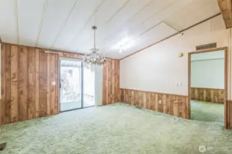 Dining room with a beautiful chandelier and a slider to the covered front porch. The primary suite entrance is on the right.