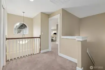 The top of the stairs shows the two story entry foyer arched window and overlook balcony style loft space, with an open area between the upstair rooms. Soft carpeting for comfort and less walking noise too.