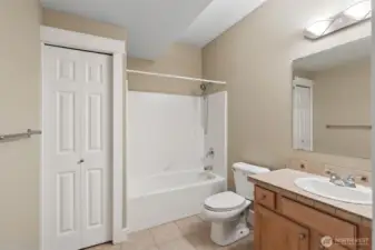 In this downstairs level full bathroom, there is plenty of space to move around, a tub surround that’s clean and practical, and a solid wood shaker vanity in a warm medium tone that adds some weight to the room. Tile floors keep things durable, while the soft muslin wall color and crisp white trim keep it feeling pulled together. Add in a linen closet with classic six panel doors and this bathroom is fully equipped for guests, movie marathons, and everyday use downstairs.