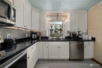 Stainless appliances, shaker cabs, and quartz counters with custom backsplash make this kitchen pop.