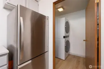 Laundry room with stacked washer dryer, water heater, and plenty of storage.