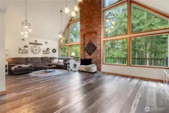 Large oversized living room with masonry wall in the center of a wall of windows facing the front of the home.