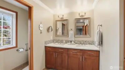 Well-appointed secondary bath with dual vanity and private water closet.