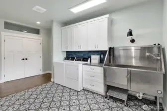 Extra-large laundry & mudroom comes complete with your own dog washing station! Behind the doors straight ahead is a large area for all your extra storage. Notice the opening above storage area that was designed to add extra storage space during the construction phase as an added element. To the right around the corner leads you to the garage.