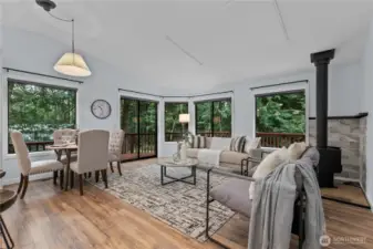 Living room with wood stove, large windows, and deck access
