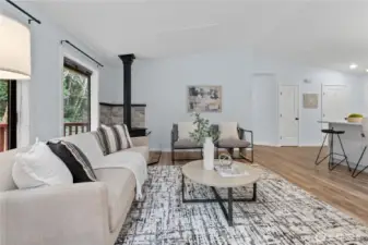 Living room and dining area with wood stove and multiple windows for natural light