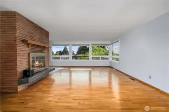 As you enter, you'll notice the wall of windows and original oak floors. Wood-burning fireplace has a gorgeous brick surround.
