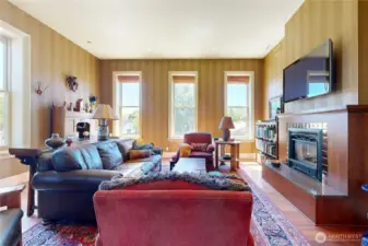 Warm and inviting living room with tall ceilings, abundant natural light, and a beautifully framed gas fireplace