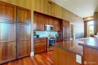 Gourmet kitchen featuring rich wood cabinetry, paneled appliances, and a smart, elegant layout—perfect for cooking with heart and hosting with ease. The expansive island offers additional prep space, seating, and a deep double sink.